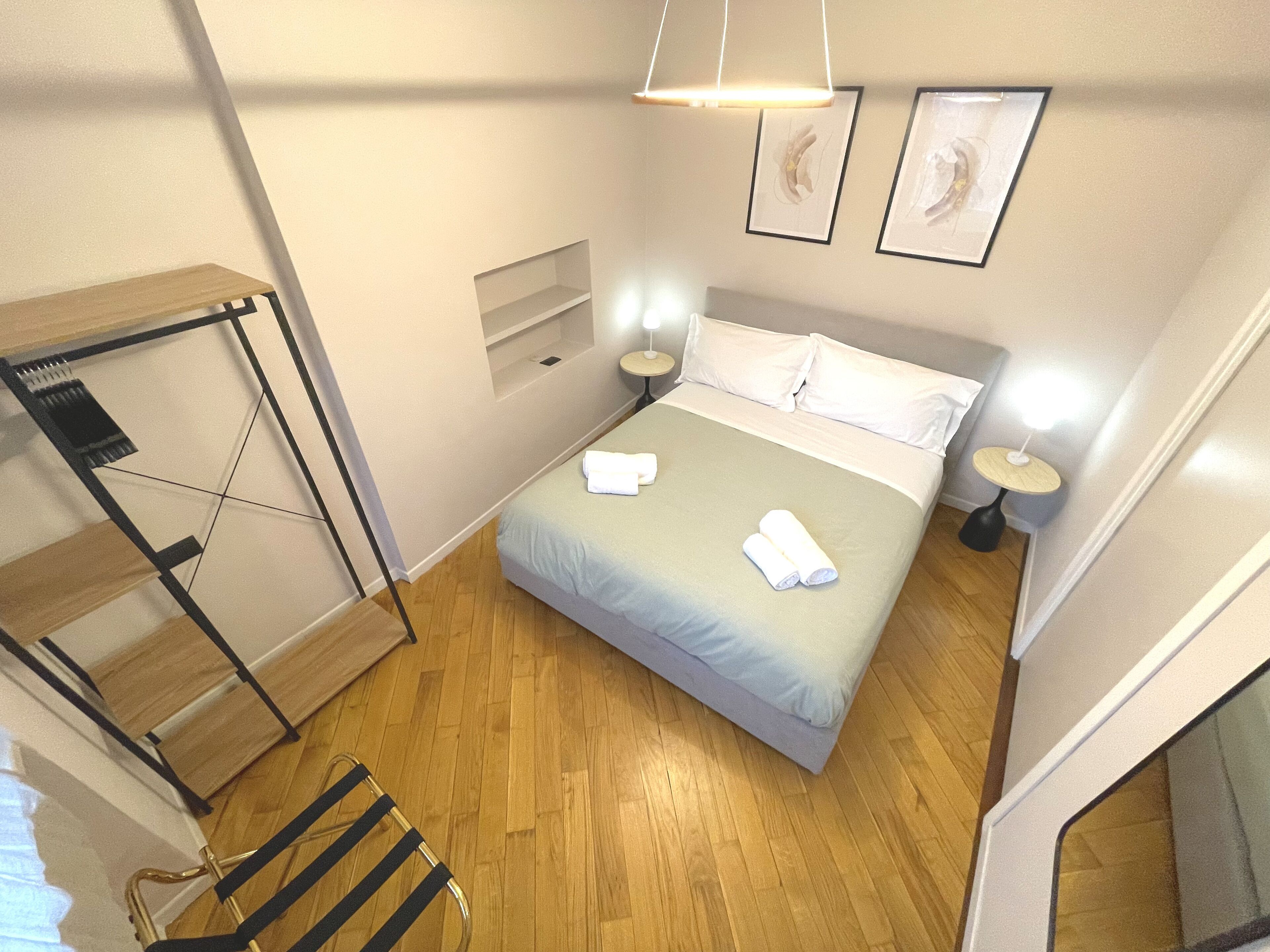 Habitación de hotel compacta con una cama, mesitas de noche, un escritorio pequeño y una silla.
