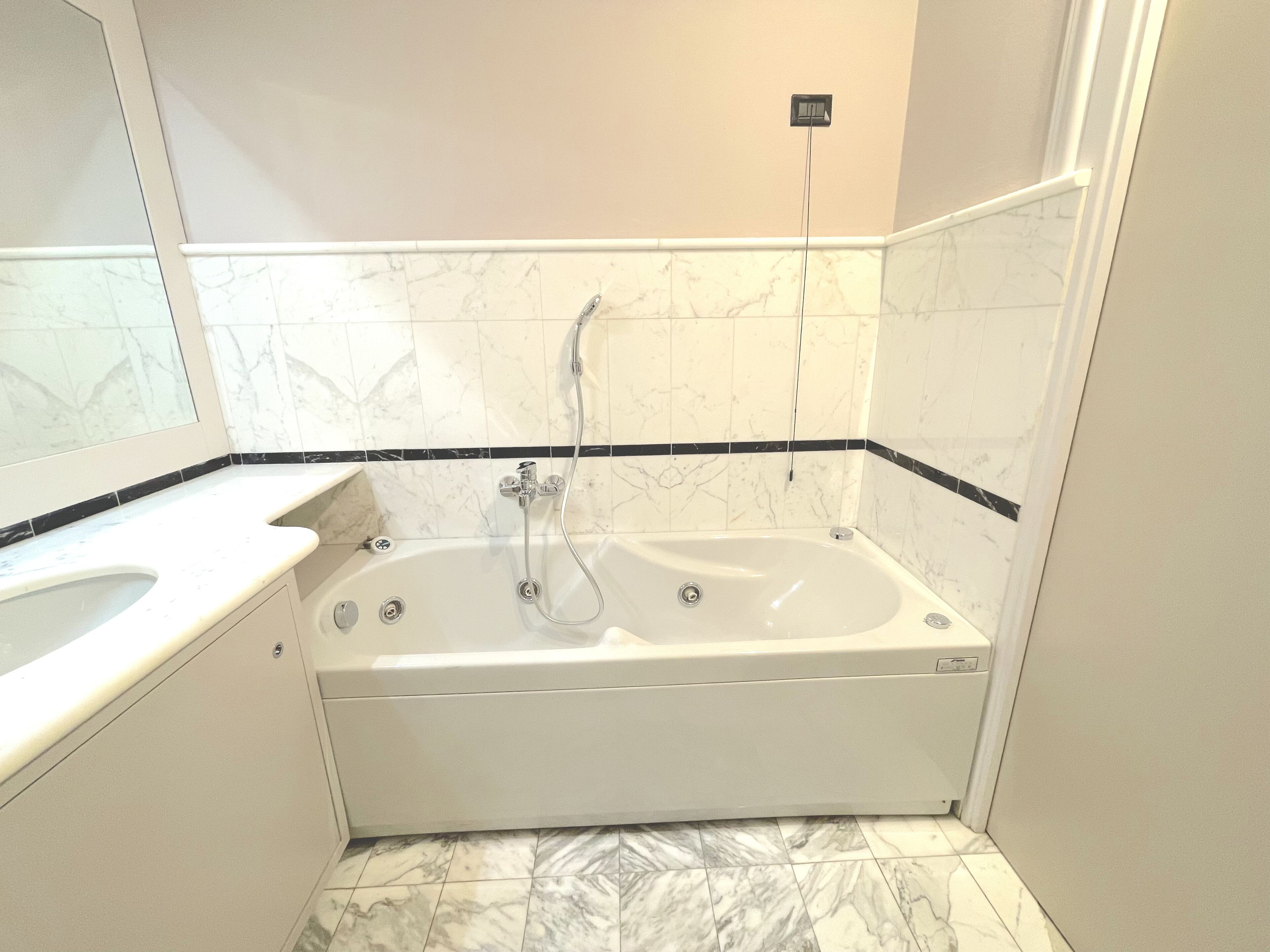 A bathroom with a bathtub, a sink, and a mirror.