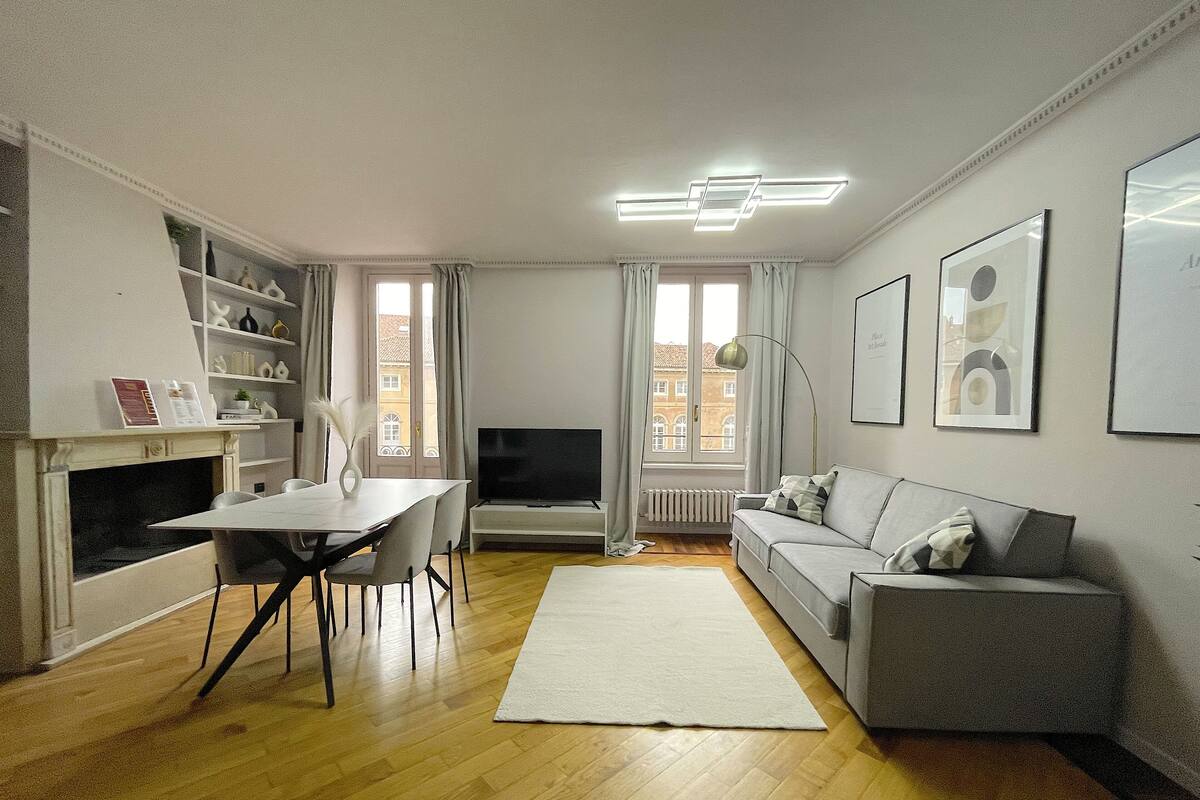 A modern living room with a dining area, a sofa, a TV, and a fireplace.