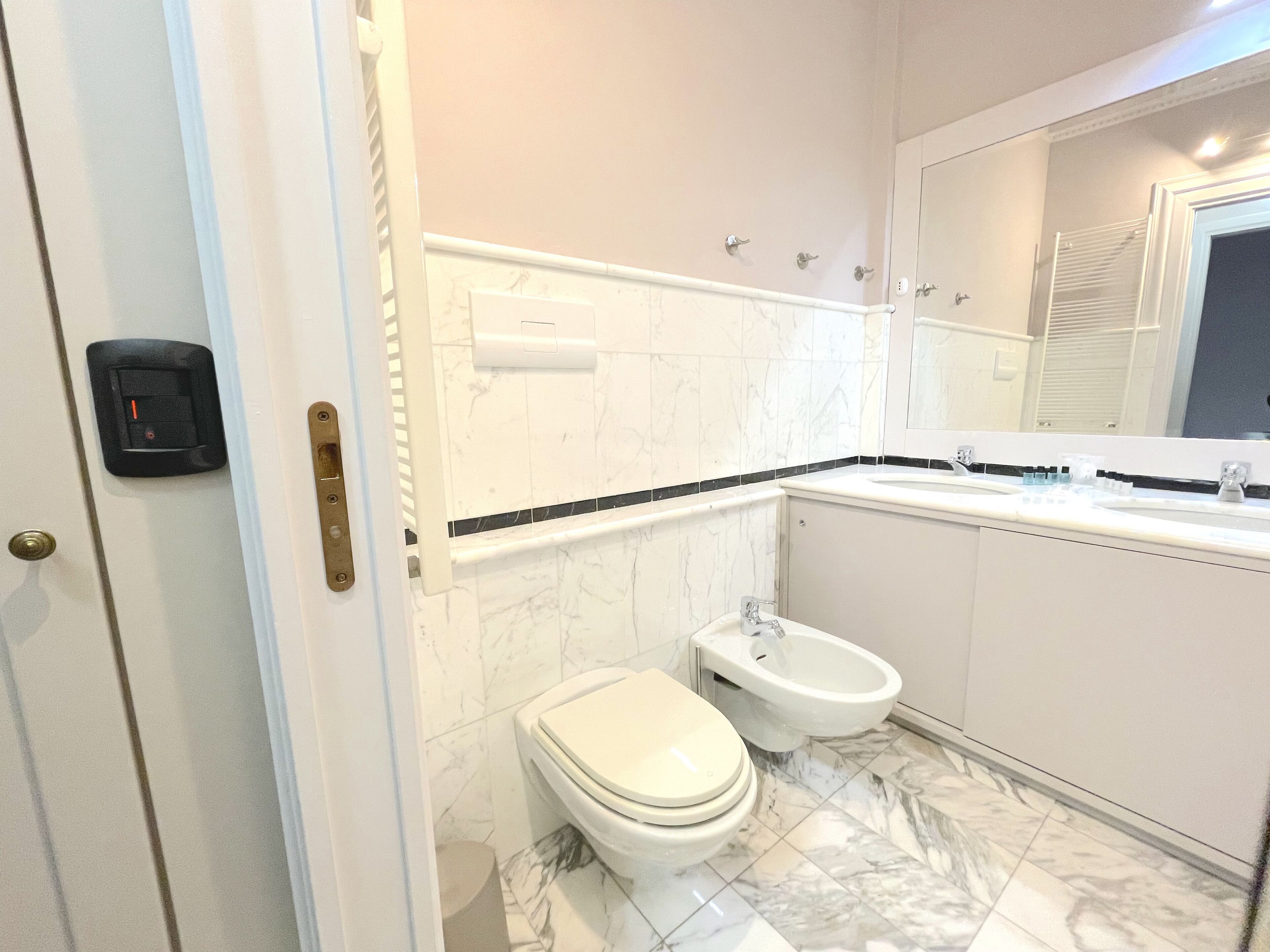 Ein modernes Badezimmer mit Toilette, Bidet und einem großen Spiegel.