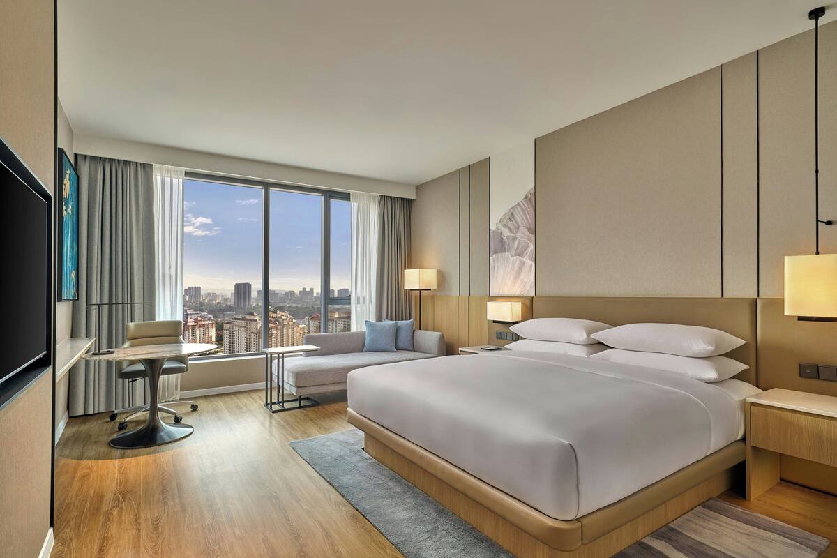 Une chambre d’hôtel moderne avec un grand lit, un bureau et une vue sur la ville.