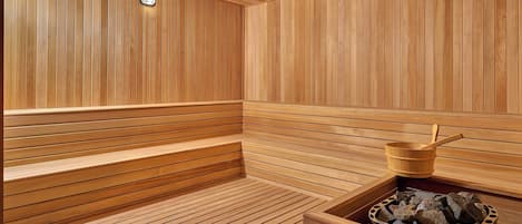 A wooden sauna with benches and a stone basin.