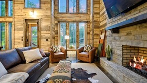 Un salón amplio con chimenea, sofás de cuero y un televisor grande montado en la pared.