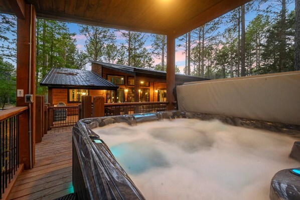 A hot tub with a wooden deck and a building in the background.