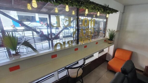 A reception area with a counter, chairs, and a window with a view of a parking lot. - HOTEL GRAN IMPERIO (Medellín)