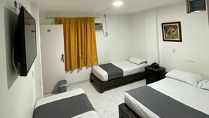 A hotel room with two single beds, a TV mounted on the wall, a small desk with a chair, and a window with curtains. - HOTEL GRAN IMPERIO (Medellín)