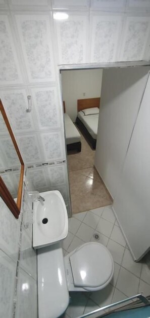 A small bathroom with a white sink, toilet, and a shower area. - HOTEL GRAN IMPERIO (Medellín)
