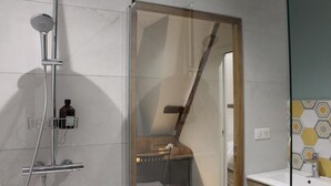 A bathroom with a glass shower enclosure, a sink, and a mirror.