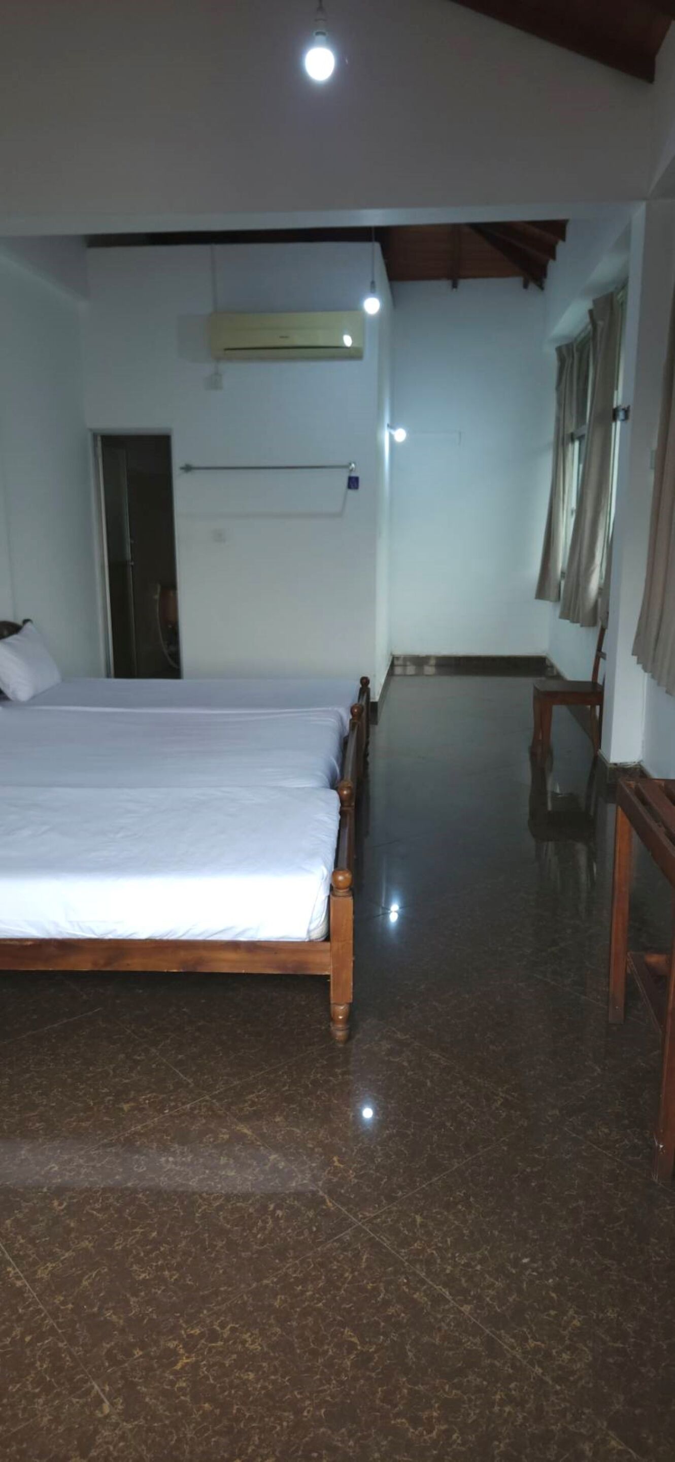 Une chambre d’hôtel avec un grand lit, une tête de lit en bois, un téléviseur à écran plat, une armoire et une petite table.