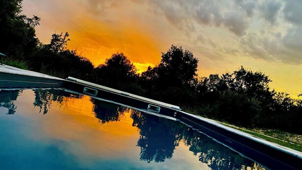 A swimming pool with a clear reflection of trees and a sunset sky. - Villa Spacieuse Avec Piscine, 3 Chambres, Proche Ardèche, Grotte Aven D'orgnac (Issirac)