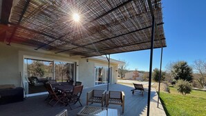 A patio with a table and chairs, a covered seating area, and a view of the surrounding landscape. - Villa Spacieuse Avec Piscine, 3 Chambres, Proche Ardèche, Grotte Aven D'orgnac (Issirac)