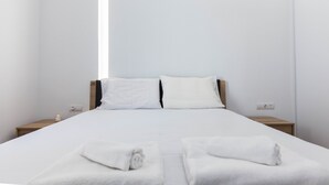 A minimalist hotel room with a large bed, two bedside tables, and a view of the sky. - Kallithea Modern Living w Designer Touch (Kallithea)
