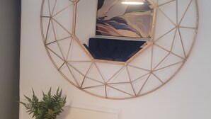 Una habitación con un espejo redondo, una planta en maceta y un mueble de madera.