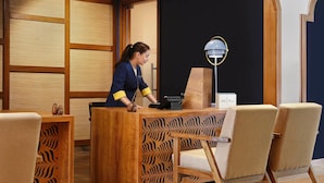 A reception desk with a wooden design, a modern lamp, and two upholstered chairs. - Voco Jim Corbett (Ramnagar)
