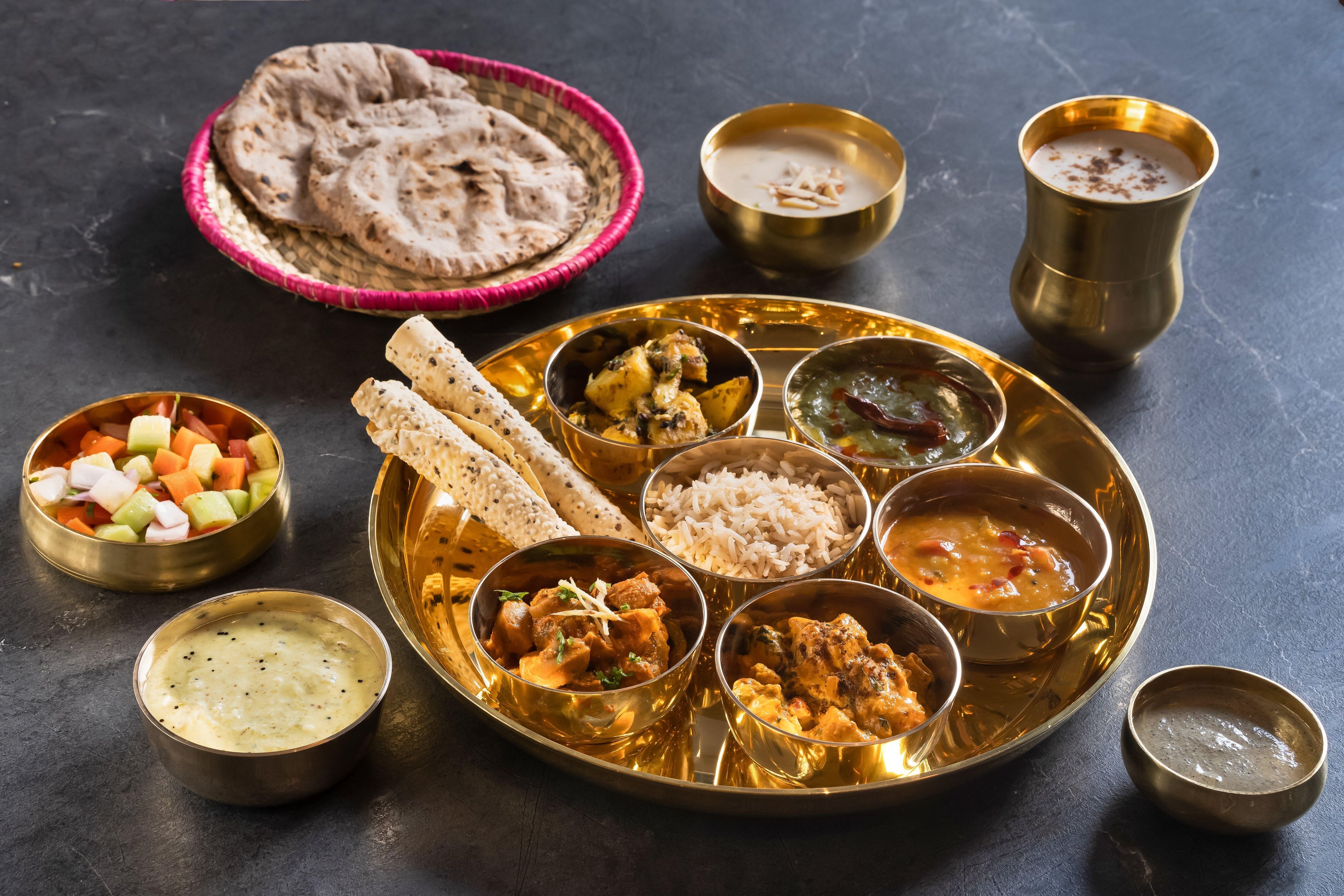 Un repas traditionnel indien composé de différents plats et de pains, servis sur un plateau doré.