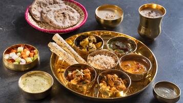 Un repas traditionnel indien composé de différents plats et de pains, servis sur un plateau doré.