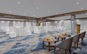 A conference room with round tables, white chairs, and a podium. - Voco Jim Corbett (Ramnagar)