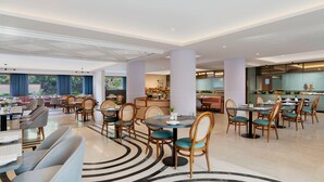 A modern hotel lobby with round tables, comfortable seating, and a central area with a counter and seating. - Voco Jim Corbett (Ramnagar)