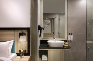 Une salle de bain moderne avec un grand miroir, un lavabo et une douche.