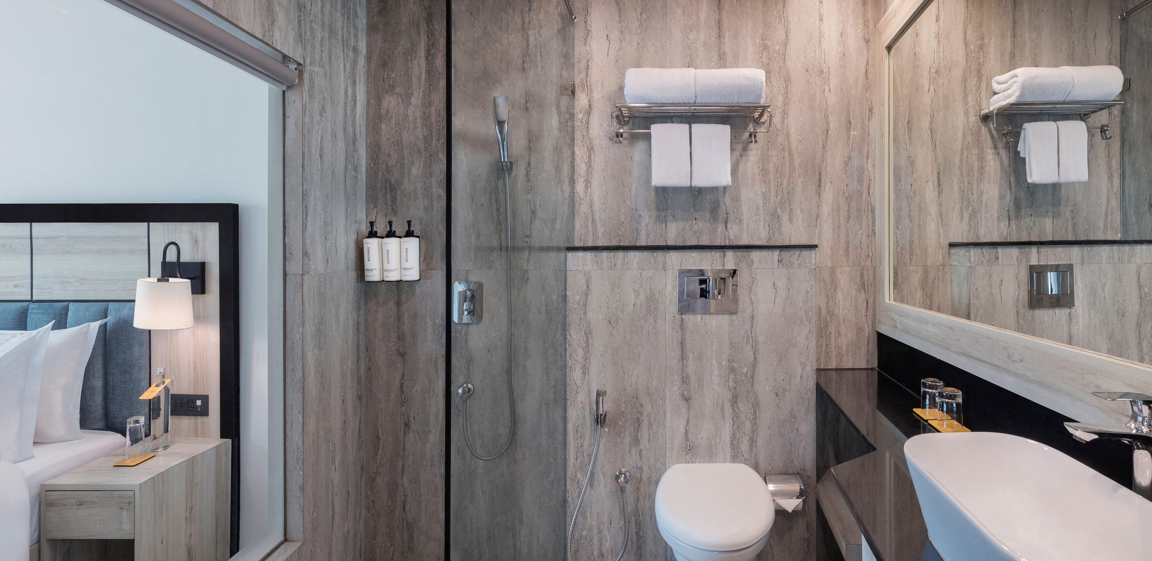 Un baño moderno con tocador de madera, un espejo grande, un inodoro y zona de ducha.