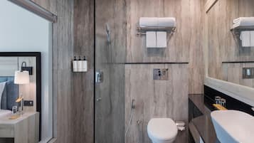 Un baño moderno con tocador de madera, un espejo grande, un inodoro y zona de ducha.
