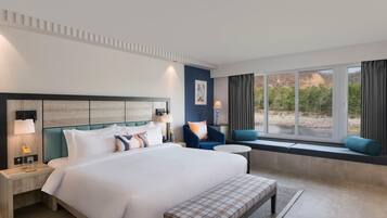 Une chambre d’hôtel moderne dotée d’un grand lit, d’un coin salon près de la fenêtre et offrant une vue sur l’extérieur.