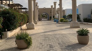 A paved courtyard with columns, potted plants, and a clear sky. - Rose beach chalet  (Aqaba)