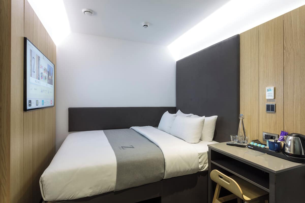 A modern hotel room with a bed, a desk, and a chair.