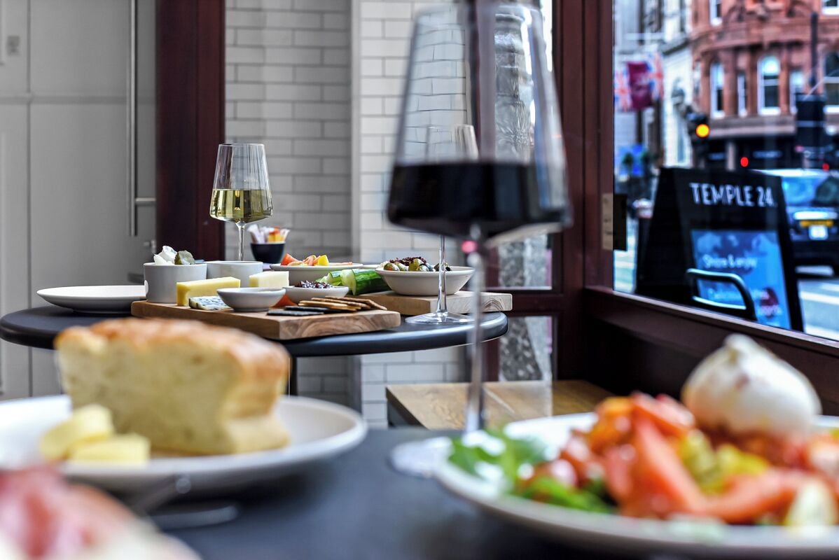 A dining table with various dishes, a wine glass, and a menu board in a restaurant setting.