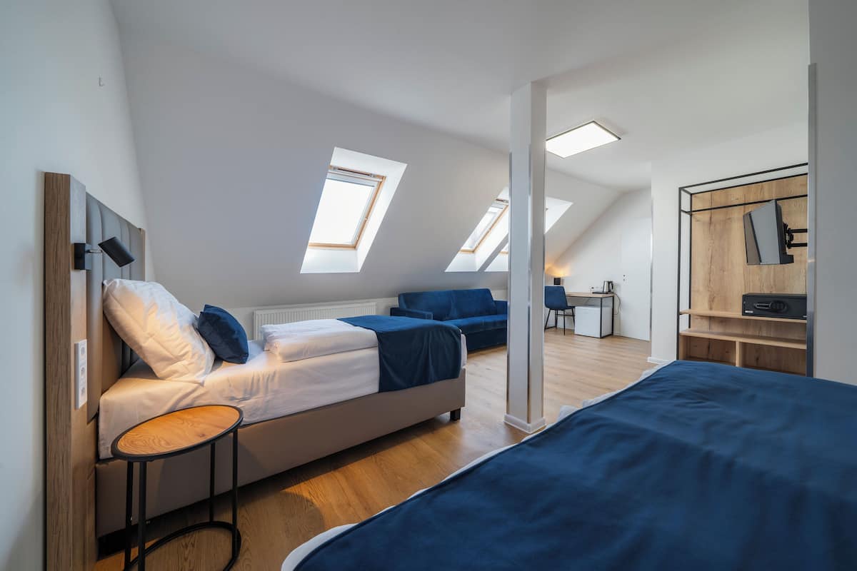 A modern loft bedroom with skylights, a bed, a desk, and a chair.