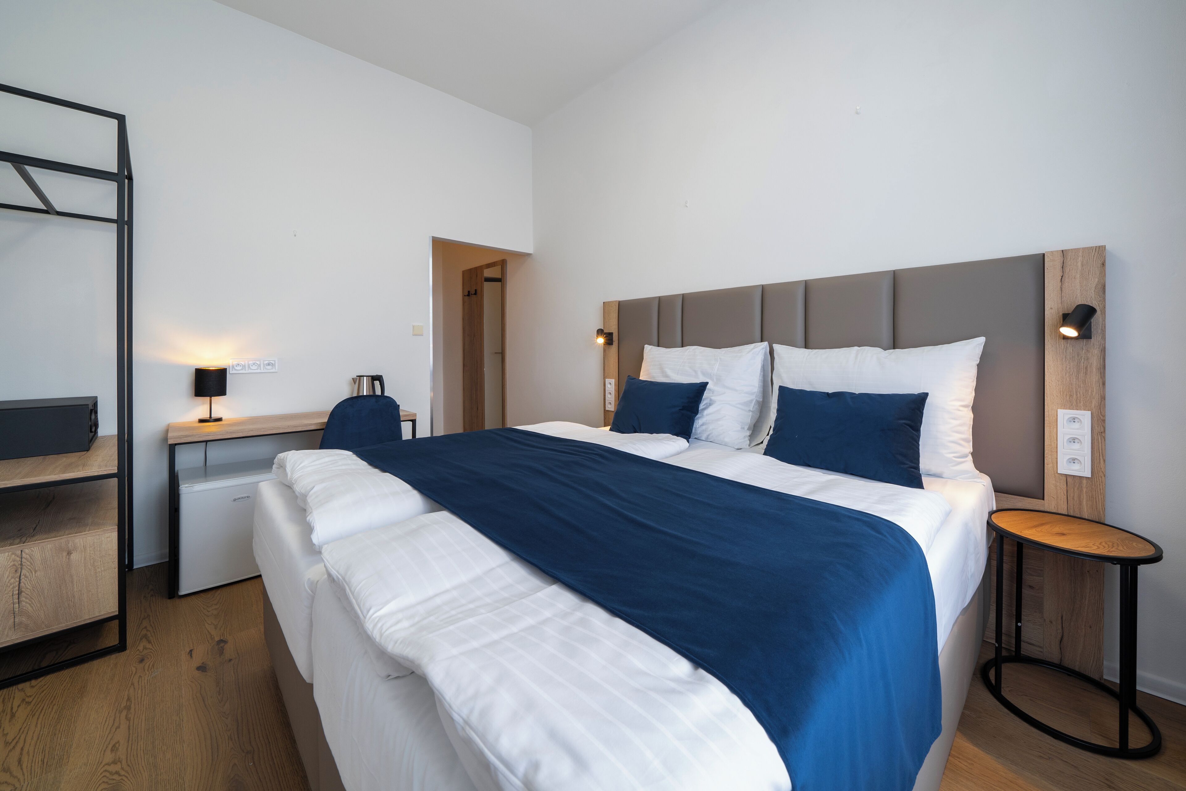 A modern hotel room with a large bed, a desk, and a small table.