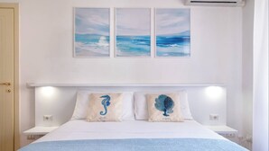 A bedroom with a bed, white walls, and three framed pictures above the bed.