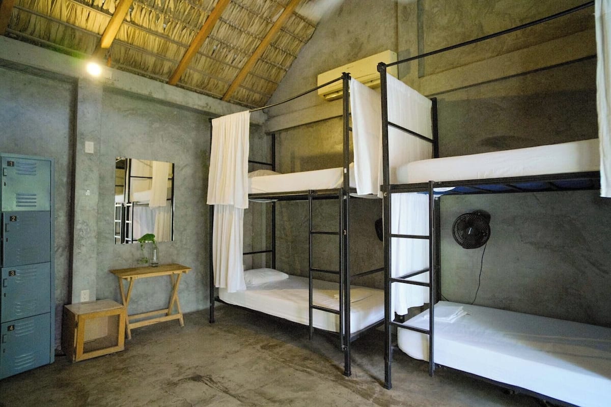 A bunk room with bunk beds, a small wooden table, a mirror, and a blue locker.