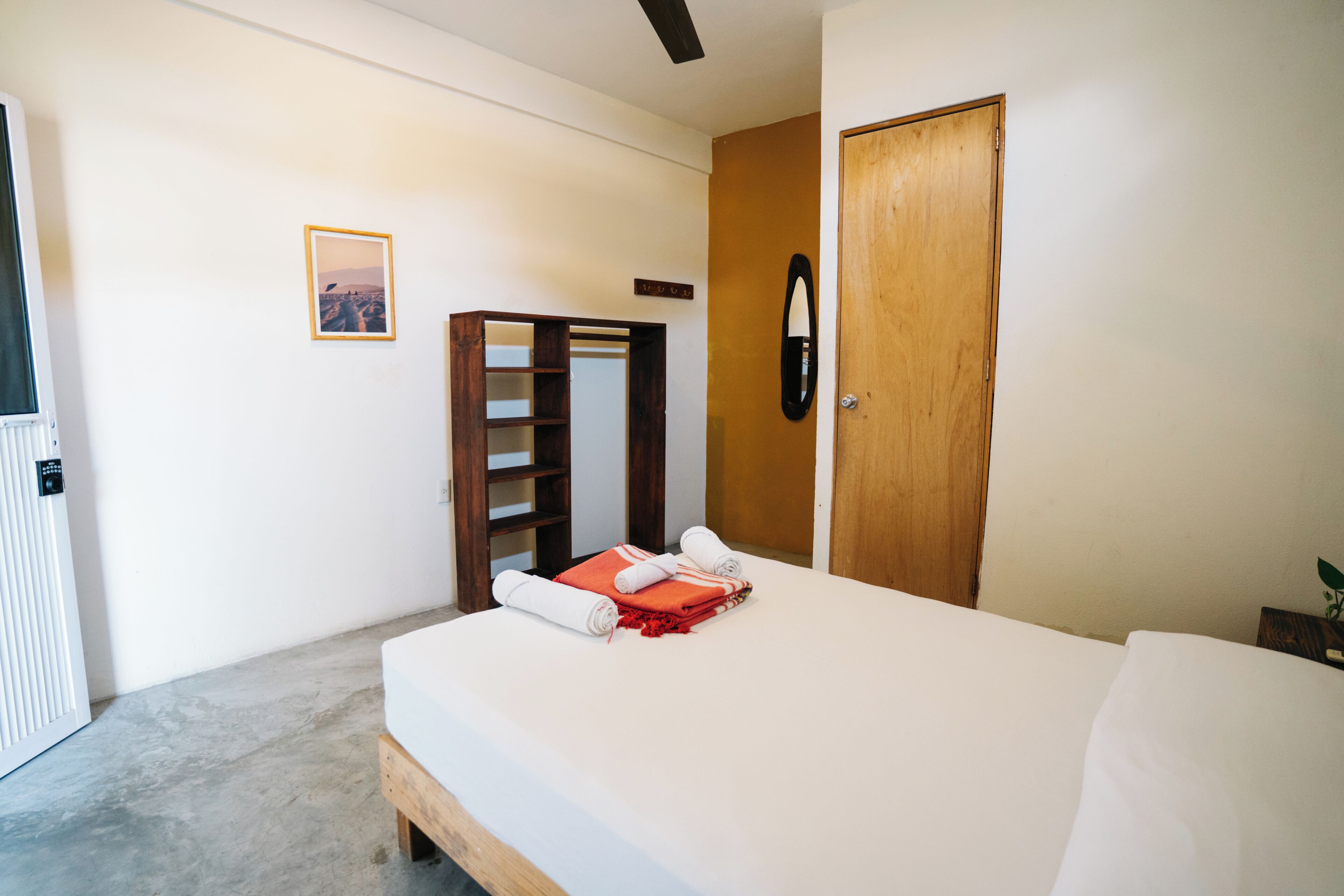 Un dormitorio con cama, un armario de madera, un espejo y un cuadro en la pared.