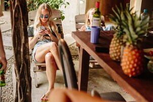 Una persona sentada a una mesa de madera con una piña y una botella de vino, evocando un ambiente de comedor informal.