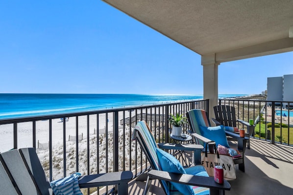 Un balcon avec coin salon extérieur, une vue sur la plage et un espace piscine.
