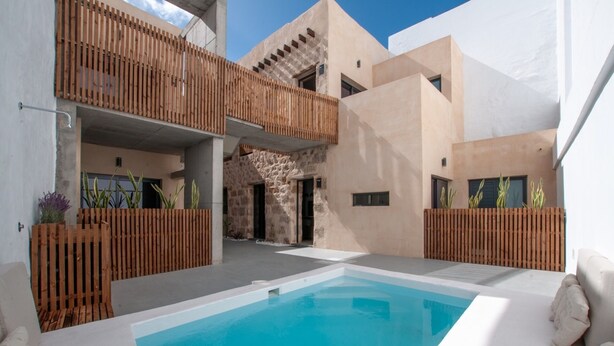 Un espace piscine moderne avec une piscine à l’eau d’un bleu limpide, des clôtures en bois et un mur en pierre.