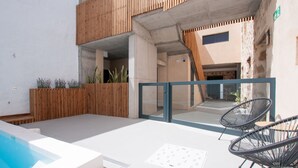 Un espace piscine aménagé sur le toit, avec un sol en béton, deux chaises en fil de fer noir et une clôture en bois.