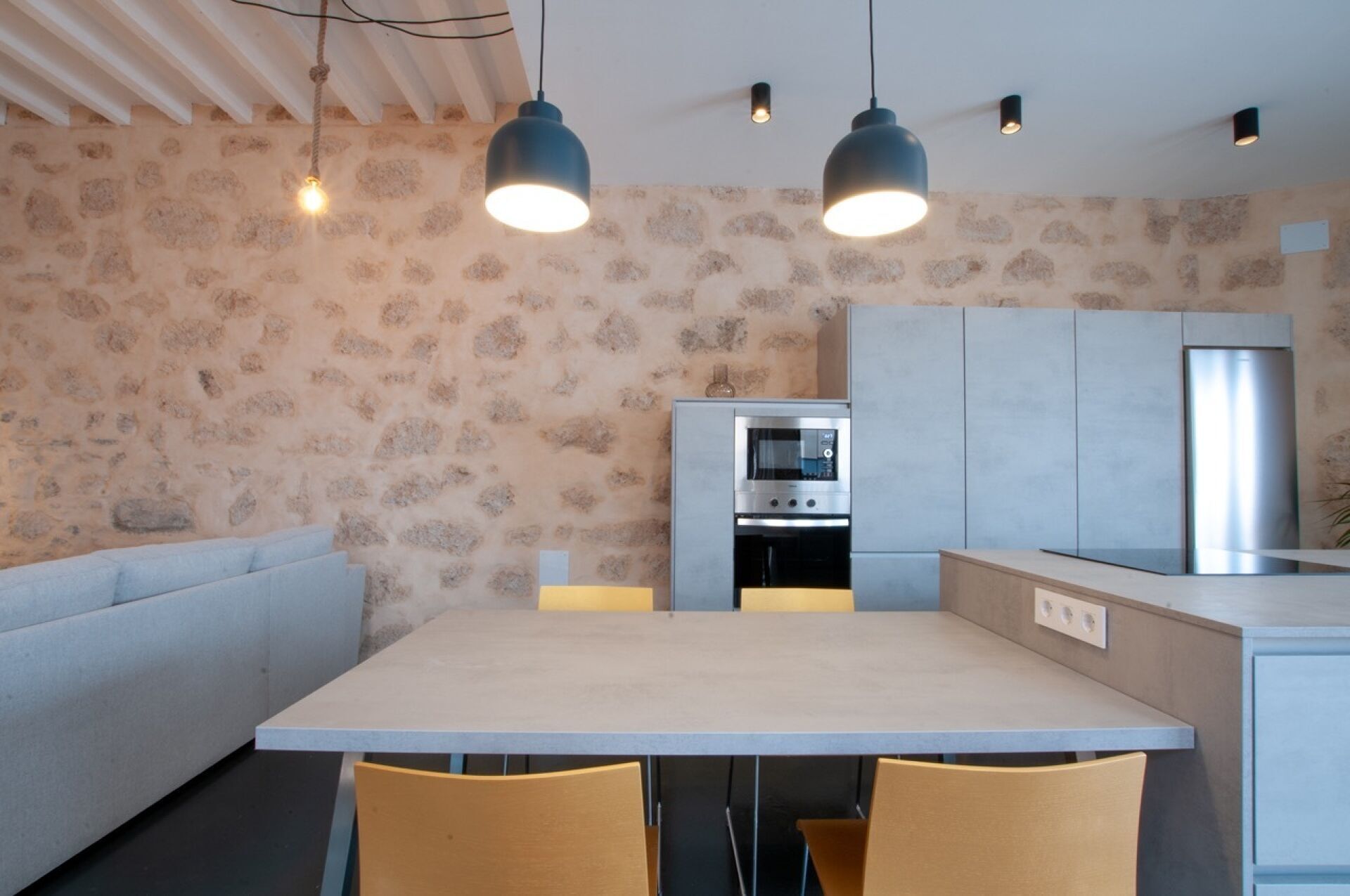 A modern kitchen with a built-in oven, a dining table with chairs, and pendant lighting.