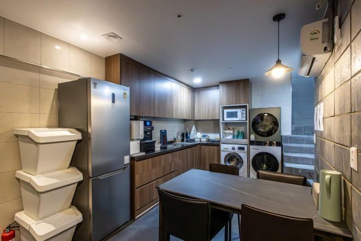 A compact kitchen with a refrigerator, microwave, and washing machine.