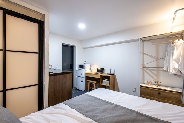 A hotel room with a bed, a desk with a computer, a microwave, and a small kitchenette. - Beyond Residence Jongno (Seoul)