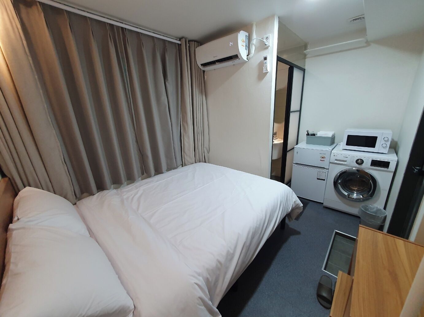 Une chambre d’hôtel équipée d’un lit, d’un climatiseur, d’un lave-linge et d’un four à micro-ondes.