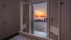 Une pièce dotée d’une grande porte-fenêtre coulissante donnant sur une vue sur la plage au coucher du soleil.