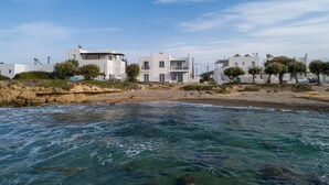 Un bâtiment situé sur la côte, doté d’une architecture moderne, et qui se trouve à proximité d’une plage rocheuse bordée d’eaux d’un bleu limpide.