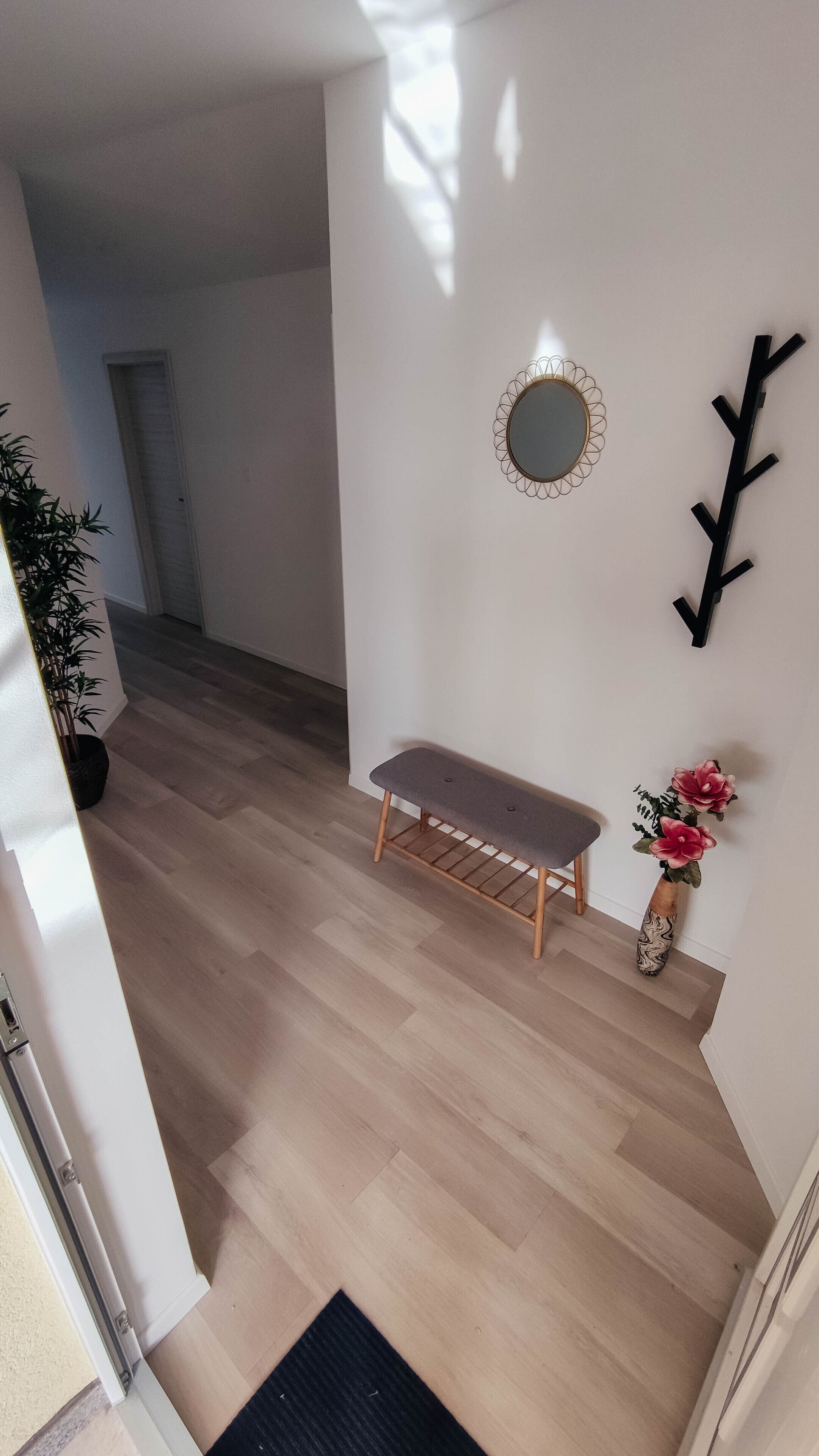 Una escalera con un banco, un espejo y un adorno en la pared.