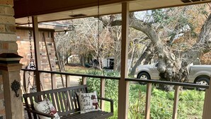 Eine Holzveranda mit einer Bank, einem Hängesessel und einer Texas-Flagge auf dem Boden.