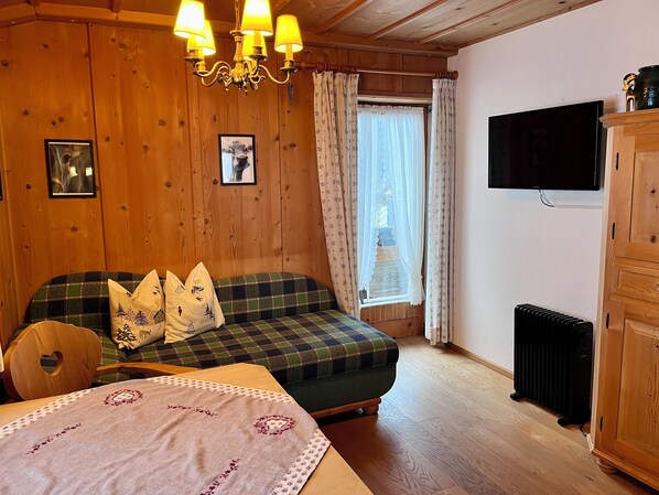 A cozy room with a plaid sofa, a wooden cabinet, and a radiator.