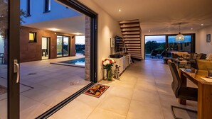 Un intérieur de maison moderne comprenant un coin repas, une cuisine et une vue sur l’extérieur.