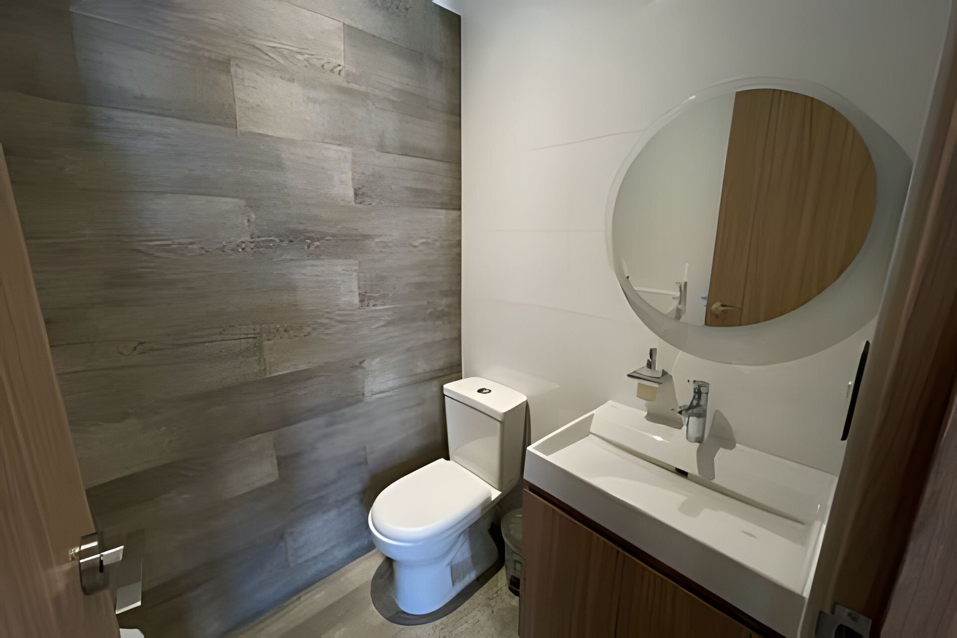 A bathroom with a toilet, a sink, and a mirror.