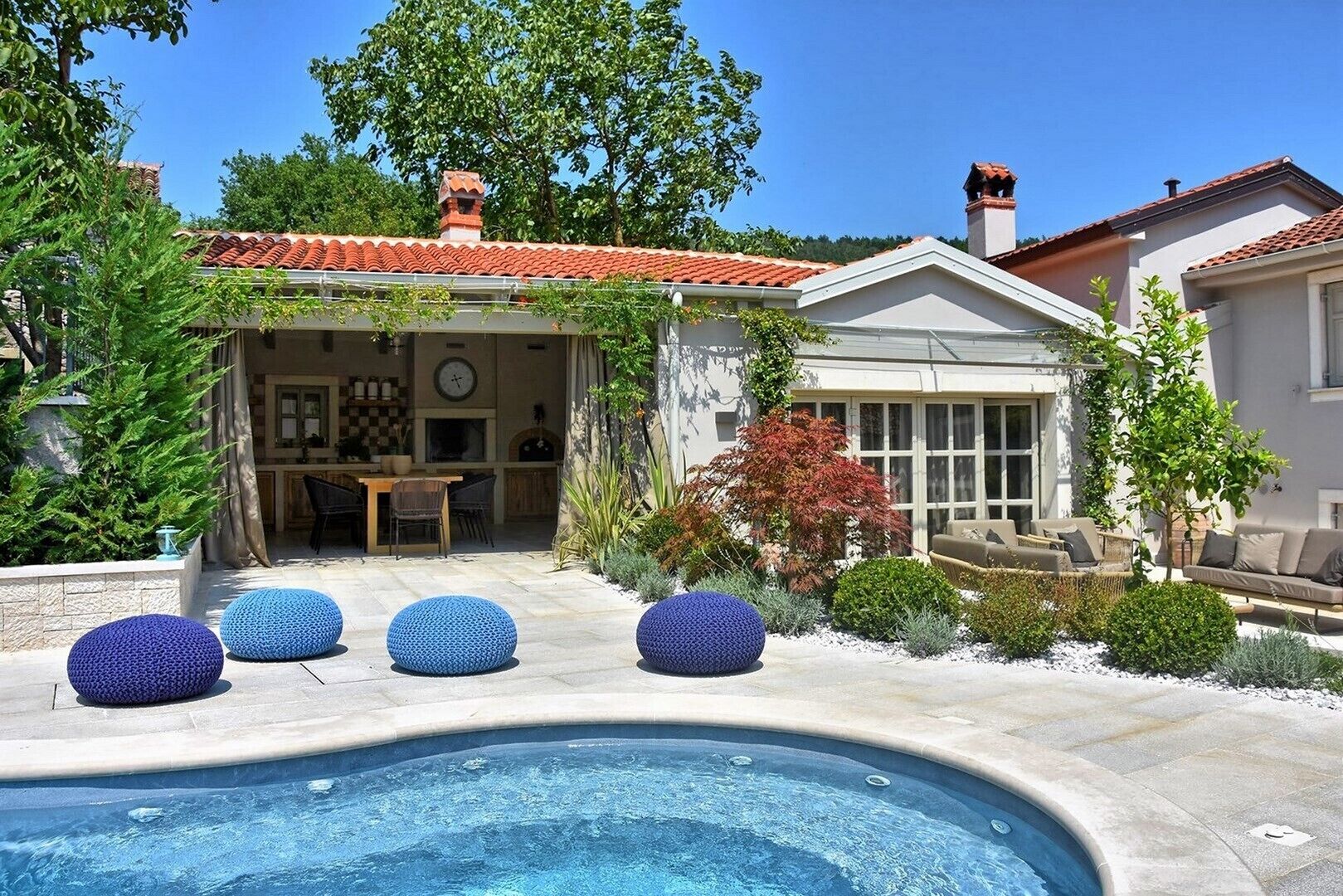A pool area with a hot tub, outdoor seating, and a covered patio.